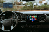 Car interior with dashboard and steering wheel, showing a smartphone app interface.
