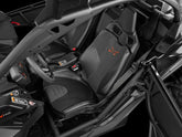 Black interior car seats with orange embroidered logos, shown inside a roll cage vehicle cabin.