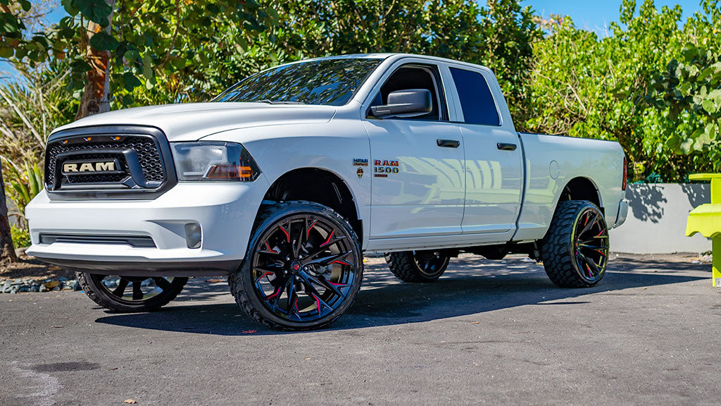 White Ram truck with large wheels on a paved road with greenery in the background