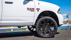 White Ram truck with black and red wheels parked by a body of water.