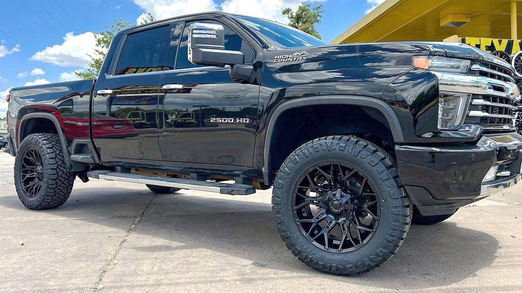 Black pickup truck with large tires on a concrete surface.