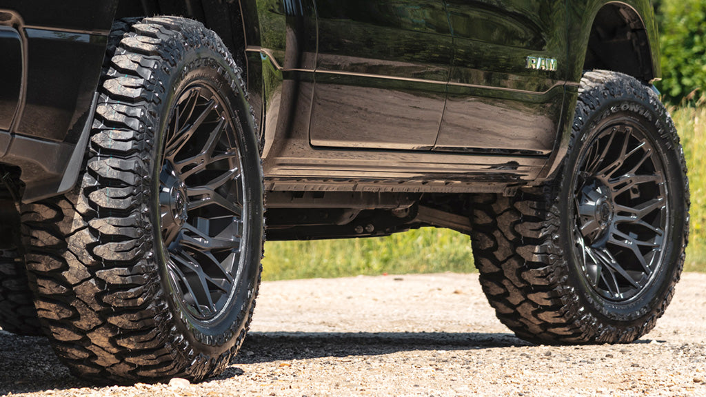 Close-up of a vehicle with large off-road tires on a road.