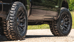 Close-up of a vehicle with large off-road tires on a road.