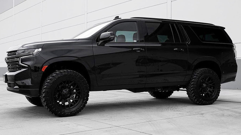 A black SUV parked on a concrete surface with a white wall background