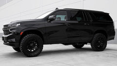 A black SUV parked on a concrete surface with a white wall background