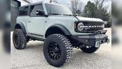 Light blue Ford Bronco SUV with off-road tires on a gravel surface.