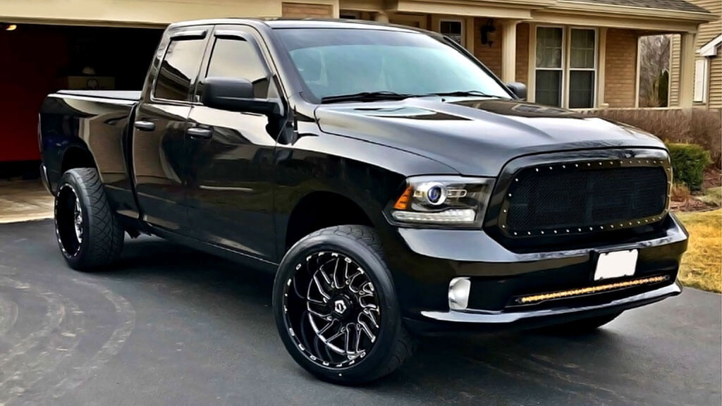 A black pickup truck With TIS 22" 544BM Custom Wheels parked on the street.