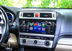 Car dashboard with a touchscreen display and various controls, brand 'subaru' visible.