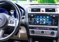 Car interior with steering wheel and dashboard displaying a touchscreen display.