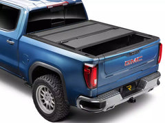 Blue GMC truck with a bakflip tonneau cover on a white background