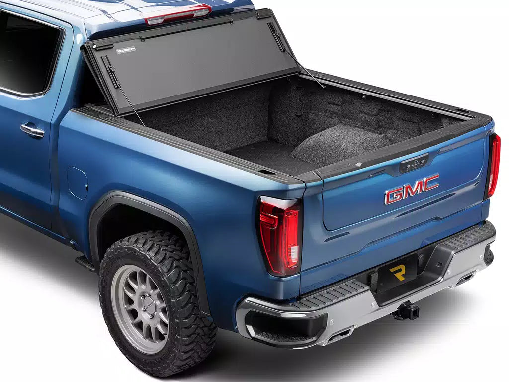 Blue GMC truck with an open bed tonneau cover on a white background