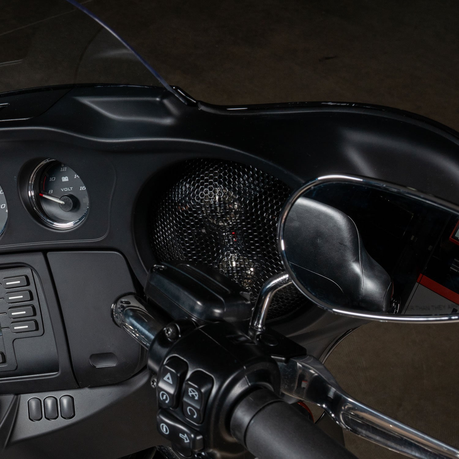 Close-up of a motorcycle handlebar with controls and mirror on a dark background