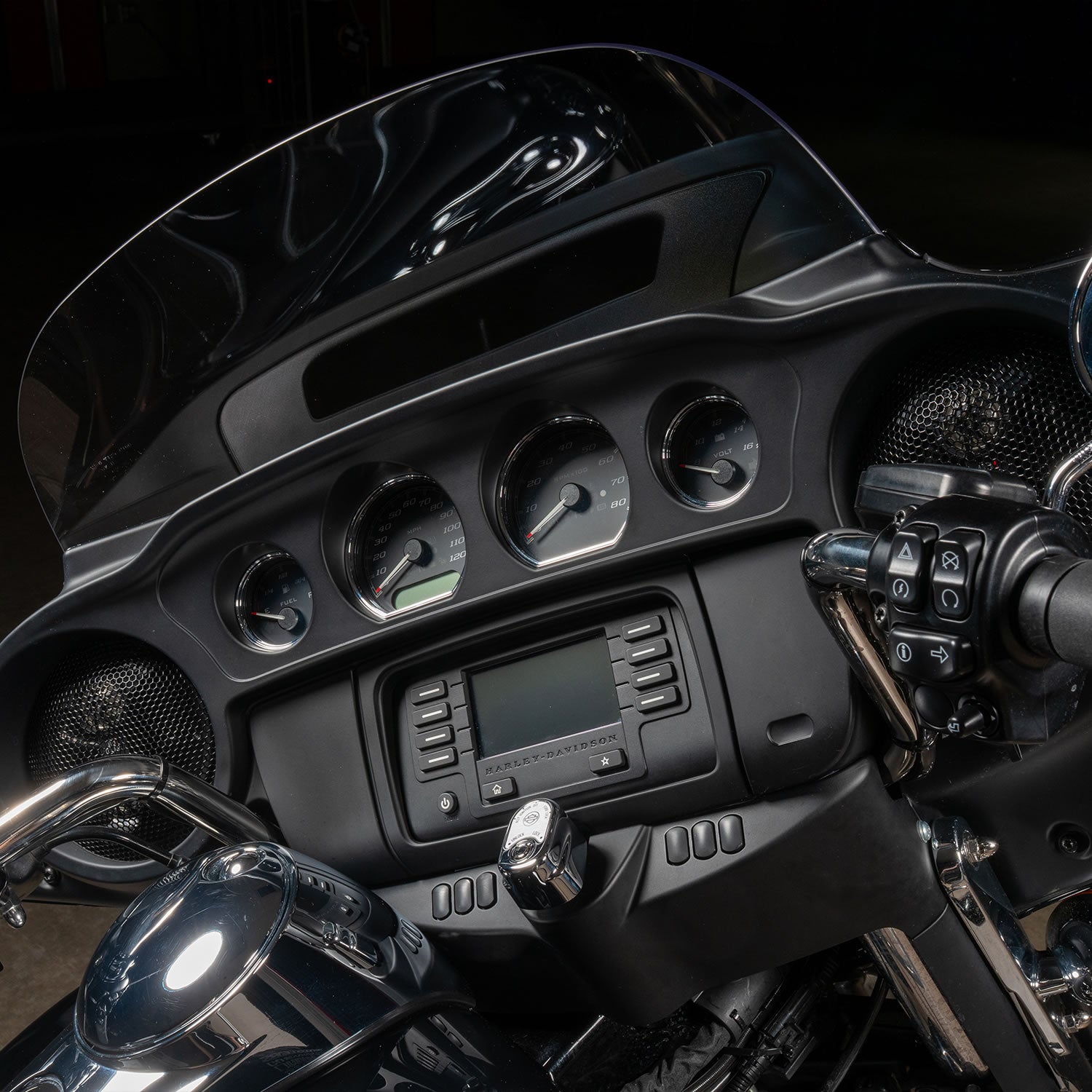 Close-up of a motorcycle dashboard with controls and display.