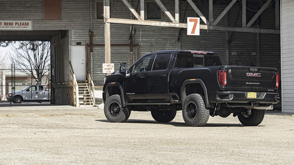 Black GMC truck parked in front of a building with a sign.