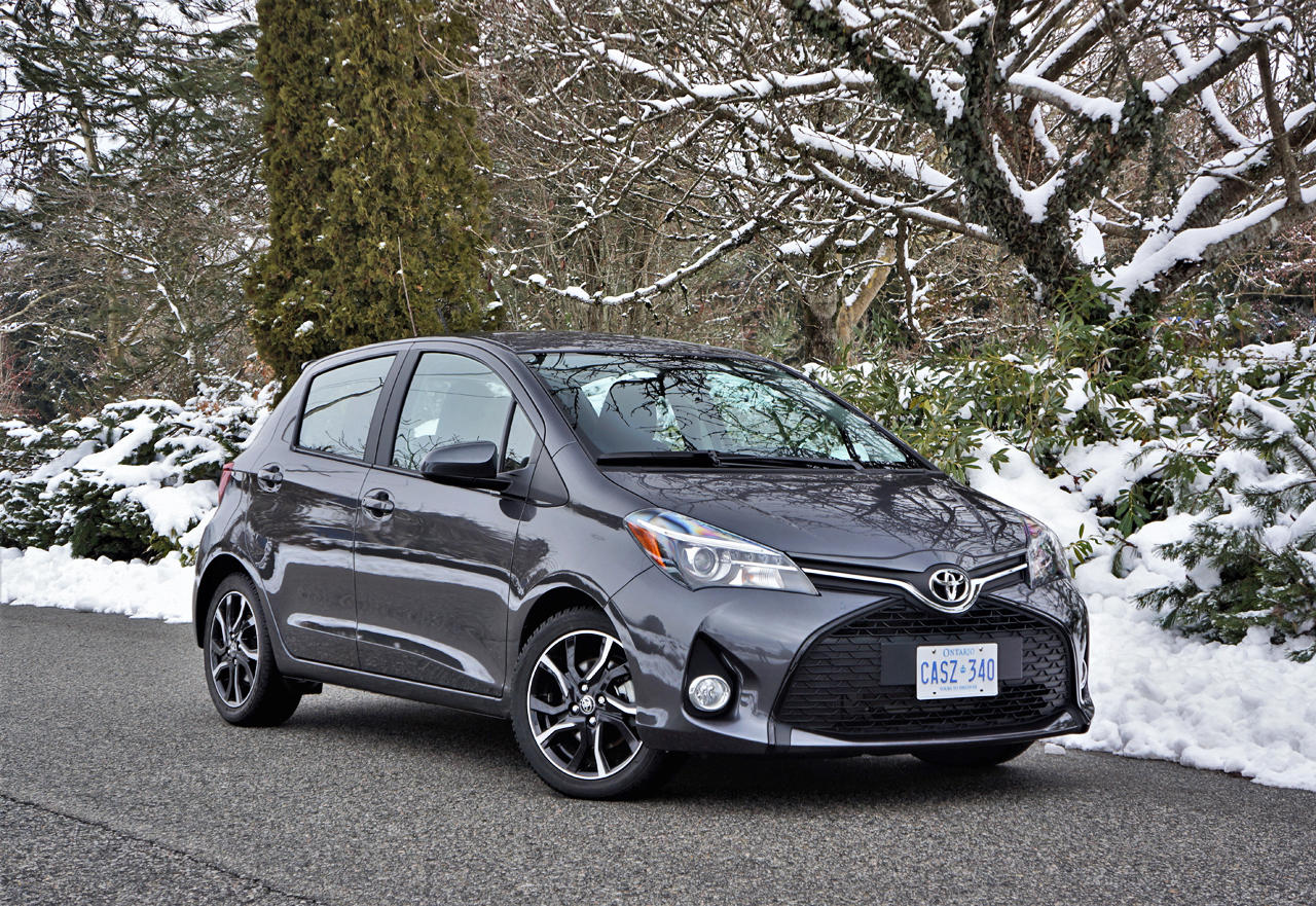 Gray Toyota car parked on a snowy road with trees and snow-covered ground in the background.