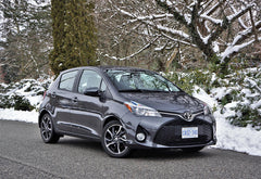 Gray Toyota car parked on a snowy road with trees and snow-covered ground in the background.