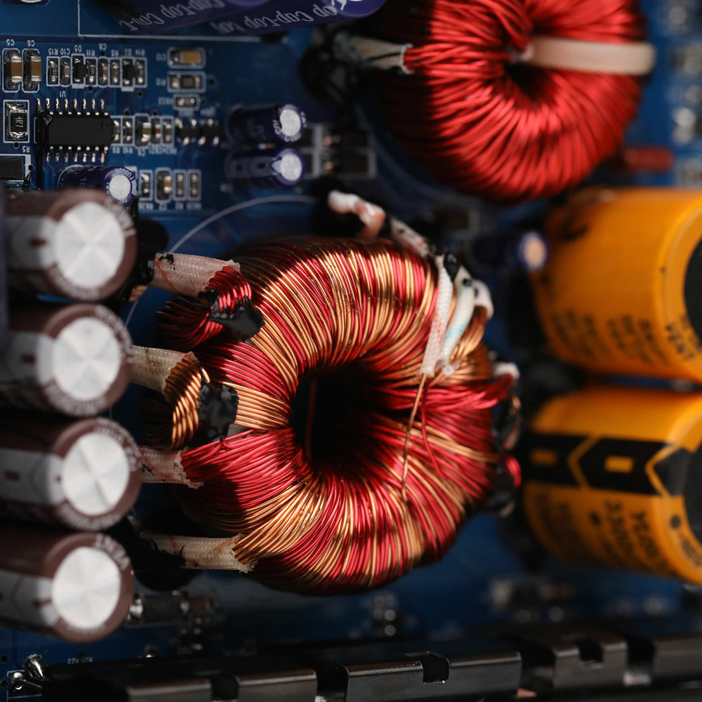 Close-up of electronic components including red and yellow coils on a blue circuit board.