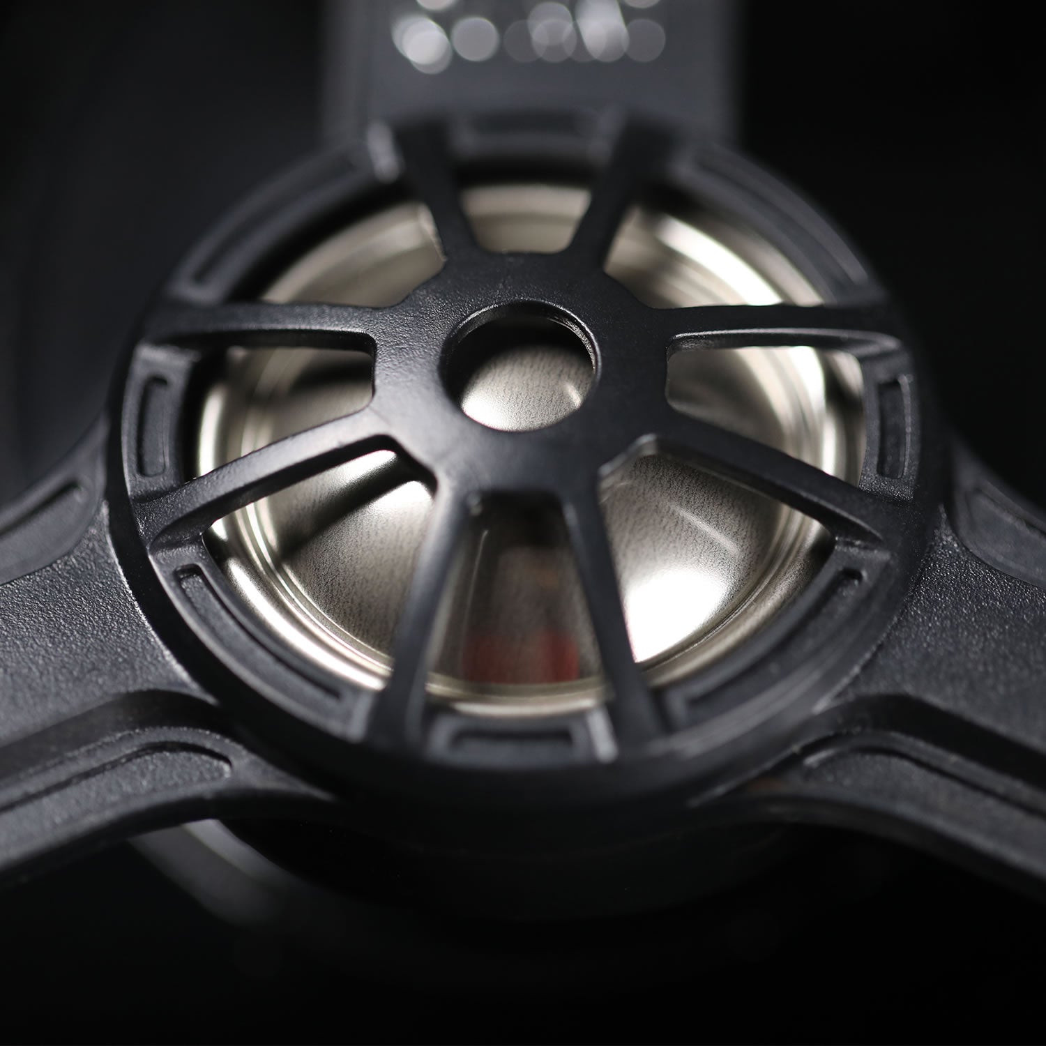 Close-up of a black speaker cone with metallic interior on a dark background