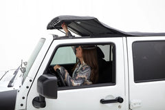 Woman sitting inside a white Jeep with the top open on a white background