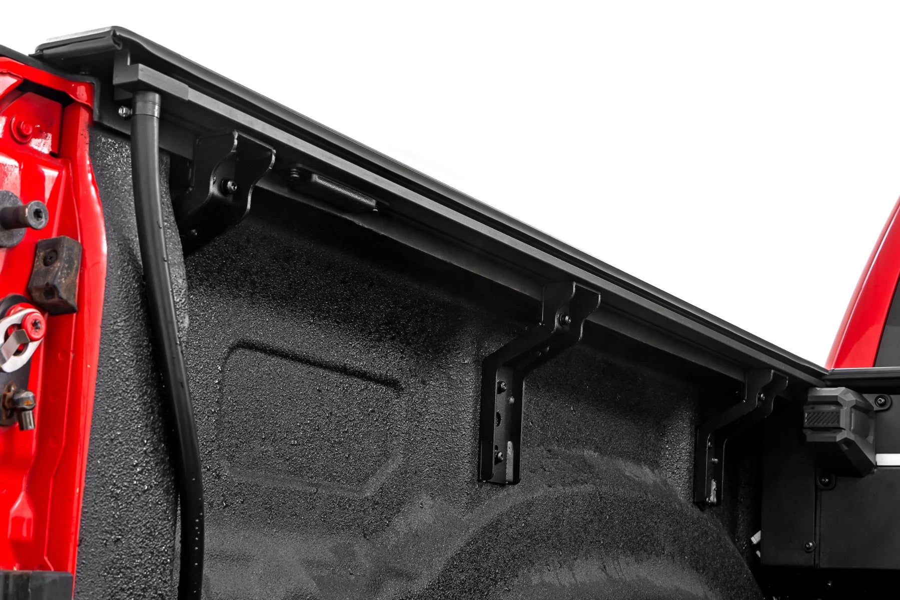 Close-up of a black truck bed liner on a red vehicle