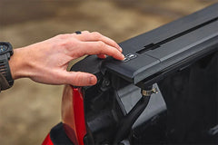 Person opening a vehicle's black roof rack with a blurred background