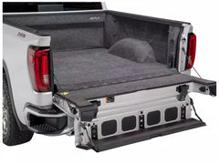 Truck bed with a gray truck bed liner and open storage compartment on a white background