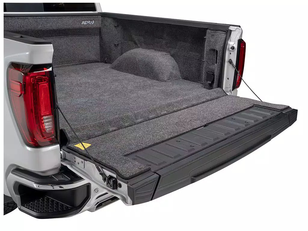 Truck bed with a gray cargo bed liner and folded flat cover on a white background
