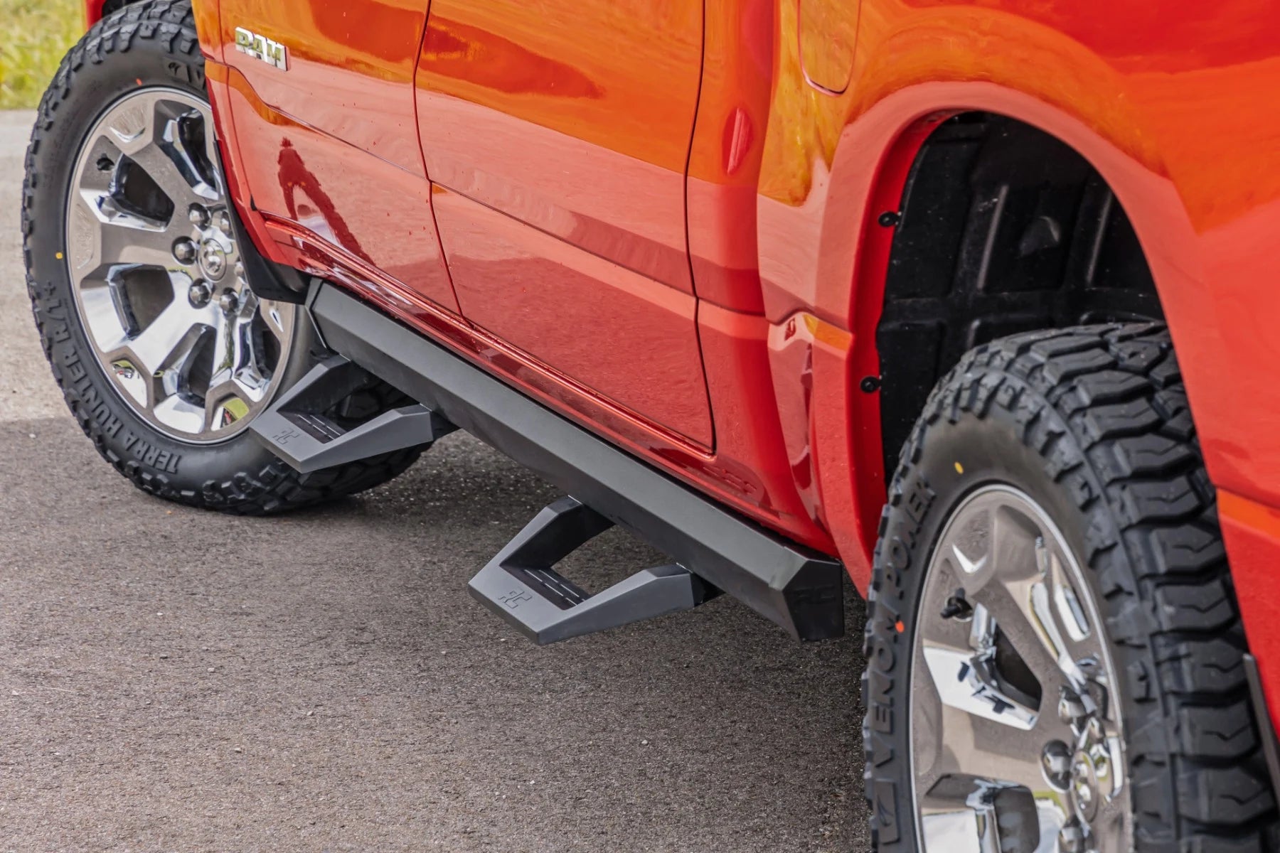 Close-up of a red truck with a step bumper on a pavement.